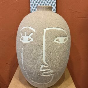 Vase de forme obus au motif visage en grès de couleur beige à l’aspect sablé
